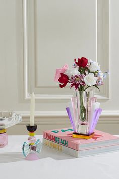 a vase filled with flowers sitting on top of a table next to a book and candle