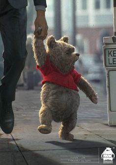 a teddy bear wearing a red sweater is being held by a man's hand