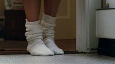 the legs and feet of a person wearing white socks, standing in front of a door