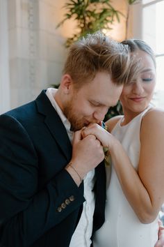 the bride and groom are looking at each other while they stand close together in front of a window