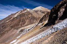 a man hiking up the side of a mountain with snow on it's sides