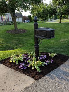 a mailbox sitting on top of a flower bed in the middle of a yard