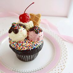 an ice cream sundae on a plate with sprinkles and a cherry