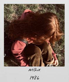 a young child sitting in the grass looking down