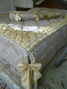 a bed with gold sheets and bows on the headboard, in a room that has carpeted flooring