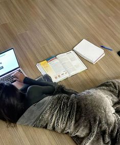 a woman is laying on the floor with her laptop and books in front of her