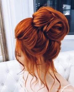 a woman with red hair is sitting on a white couch and has her back to the camera