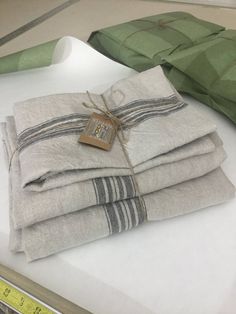 folded linens on display in a store with measuring tape and green pillows behind them