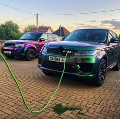 two range rovers parked in a parking lot, one is green and the other is purple