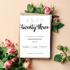 a white card with the words twenty three on it next to flowers and greenery
