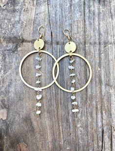 the large hoop earrings are adorned with white beads and gold plated metal hooks, which hang from a wooden plank