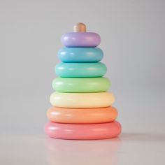 a stack of colorful plastic toys on a white surface with a wooden stick sticking out of the top