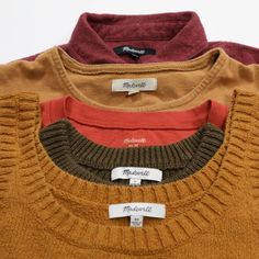 three sweaters with labels on them sitting next to each other