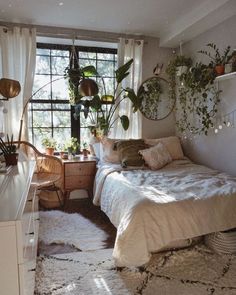 a bed room with a neatly made bed and plants on the window sill next to it