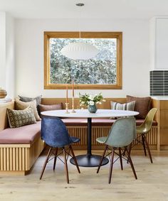 a dining room table with four chairs and a bench in front of the window,