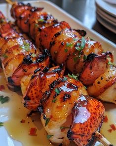 a plate topped with meat and veggies on skewers covered in sauce