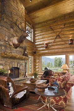 a rustic living room with stone fireplace and deer head on the wall