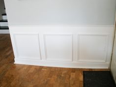 an empty room with white paneling and wood flooring on the side of the wall