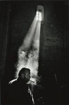 a man standing in front of a brick wall with a light coming from the window