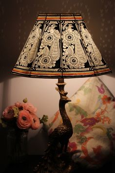 a lamp that is sitting on a table next to a vase with flowers in it