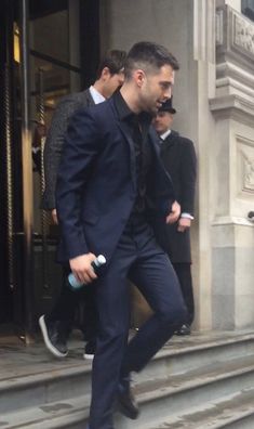 a man in a suit and tie walking down some steps with other men behind him