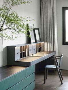 a desk with drawers and a tree in the corner