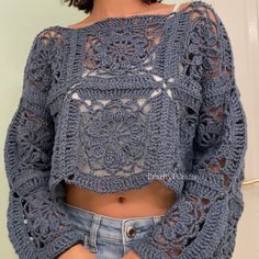 a woman is wearing a crochet top and denim shorts with her hands in her pockets