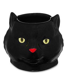 a black cat shaped vase with yellow eyes