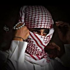 a woman wearing a red and white hijab covering her face with both hands