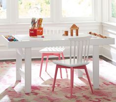 a white table with pink chairs and candy bars on it in front of two windows