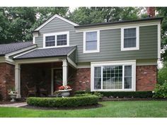 a house with green grass and trees in the background