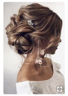 a woman with her hair in a low bun and some flowers on top of her head