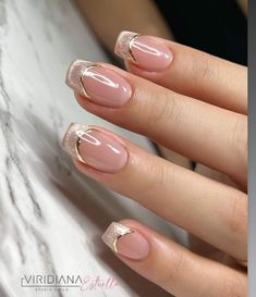 a woman's hand with pink and gold french manies on her nails,