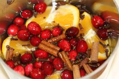 cranberries, oranges and cinnamon sticks are mixed together in a pot with water