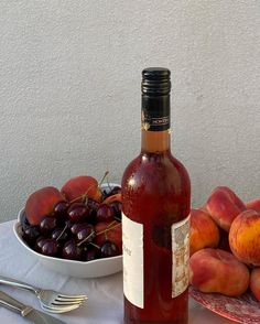 a bottle of wine sitting on top of a table next to a bowl of fruit
