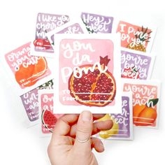 a person holding up some stickers with fruit on them and the words i love you pomegranate