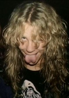 a woman with long hair sticking out her tongue and making a funny face at the camera