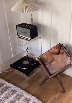 a record player sitting on top of a wooden floor next to a chair and lamp