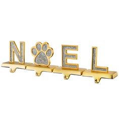 a gold metal shelf with a dog's paw on it and the word noel spelled in silver glitter