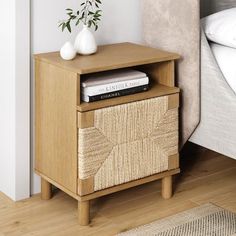 a nightstand with books on it next to a bed