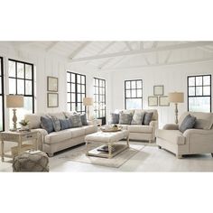 a living room filled with lots of furniture and pillows on top of a white floor