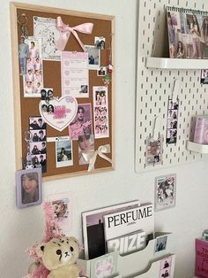 a teddy bear is sitting on a desk with many pictures and magnets attached to the wall