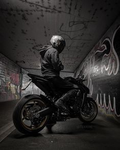 a man riding on the back of a motorcycle in a tunnel with graffiti all over it