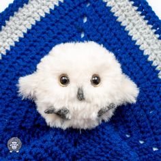 an owl is peeking out from behind a blue crocheted blanket with a white face