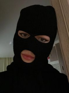 a woman wearing a black ski mask and looking at the camera