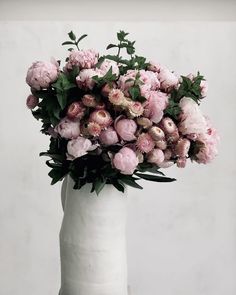 a white vase filled with lots of pink flowers