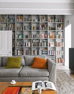 a living room filled with furniture and lots of bookshelves full of books on top of them