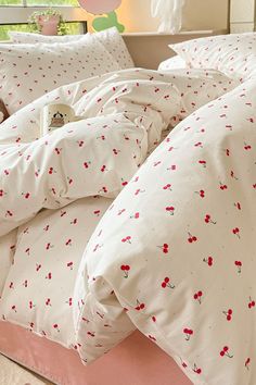 an unmade bed with white sheets and red flowers