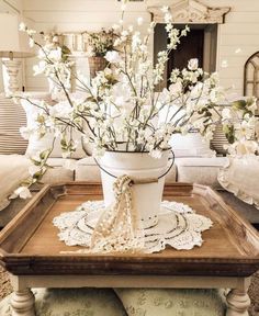 white flowers in a bucket sitting on a tray with lace doily around the edges