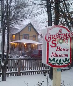 a christmas story house museum sign in front of a wooden fence with snow on the ground